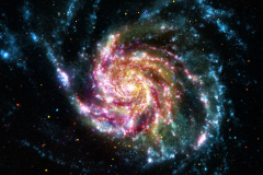 This image of the Pinwheel Galaxy, or M101, combines data in the infrared, visible, ultraviolet and x-rays from four of NASA’s space telescopes. This multi-spectral view shows that both young and old stars are evenly distributed along M101’s tightly-wound spiral arms. Such composite images allow astronomers to see how features in one part of the spectrum match up with those seen in other parts. It is like seeing with a regular camera, an ultraviolet camera, night-vision goggles and X-Ray vision, all at once! The Pinwheel Galaxy is in the constellation of Ursa Major (also known as the Big Dipper). It is about 70% larger than our own Milky Way Galaxy, with a diameter of about 170,000 light years, and sits at a distance of 21 million light years from Earth. This means that the light we’re seeing in this image left the Pinwheel Galaxy about 21 million years ago - many millions of years before humans ever walked the Earth.  The red colors in the image show infrared light, as seen by the Spitzer Space Telescope. These areas show the heat emitted by dusty lanes in the galaxy, where stars are forming. The yellow component is visible light, observed by the Hubble Space Telescope. Most of this light comes from stars, and they trace the same spiral structure as the dust lanes seen in the infrared. The blue areas are ultraviolet light, given out by hot, young stars that formed about 1 million years ago. The Galaxy Evolution Explorer (GALEX) captured this component of the image. Finally, the hottest areas are shown in purple, where the Chandra X-ray observatory observed the X-ray emission from exploded stars, million-degree gas, and material colliding around black holes.